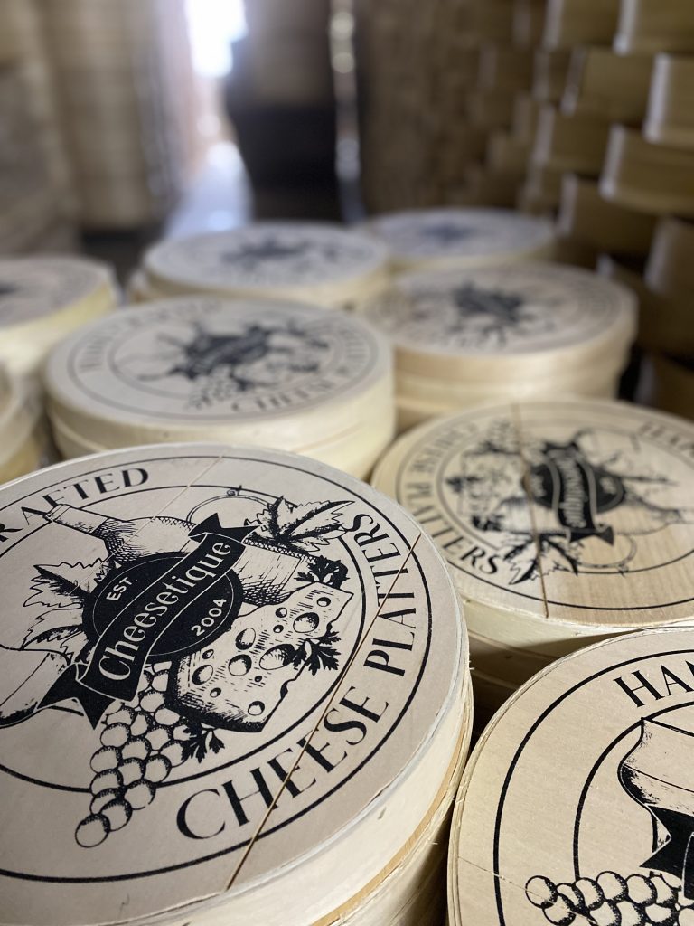 Wooden bins for cheese products with silk screening for a specific brand on the top of each bin.